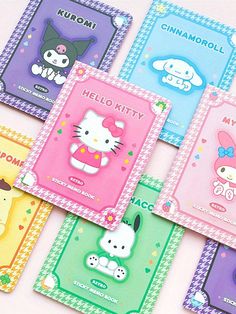 four hello kitty notebooks are lined up on a pink tablecloth with cartoon characters