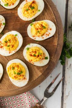 deviled eggs are arranged on a wooden platter