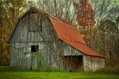 an old barn with a red roof in the woods