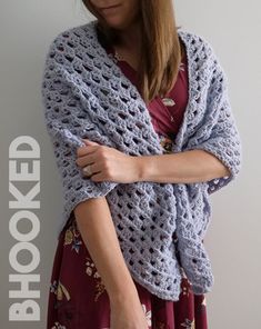 a woman is wearing a crocheted shawl and holding her hand on her hip