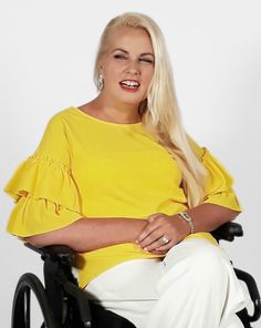 a woman sitting in a wheel chair with her hands on her hips and smiling at the camera