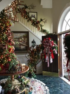 a decorated christmas tree sitting in the corner of a living room next to a staircase