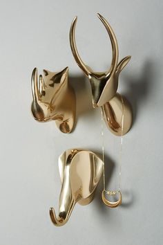 three gold metal animal hooks on a white wall