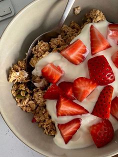 a bowl filled with yogurt, strawberries and granola