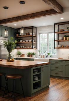 a large kitchen with green cabinets and wooden floors is pictured in this image, there are two stools at the center of the island