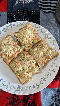 four pieces of bread on a plate with flowers and leaves around it, sitting on a table cloth