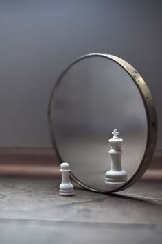 a mirror with a chess piece in front of it and a white pawn standing next to it