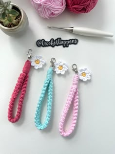 three crochet keychains with flowers on them next to a ball of yarn