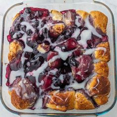 a casserole dish with blueberries and cream drizzled on top