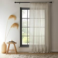 a window with sheer curtains in front of it and a rug on the floor next to it