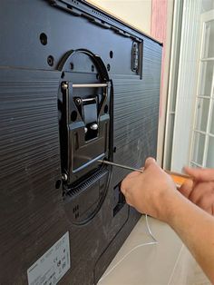 a person is using a needle to attach the back of a television screen with wires