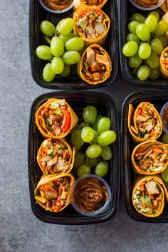 four black trays filled with different types of food and some grapes on the side