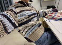 a woman sitting at a desk with a laptop computer in front of her, wearing a knitted sweater