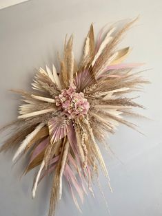 dried flowers are arranged on the wall in front of a white wall with pink accents