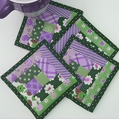 purple and green placemats on a white table with a cup next to them