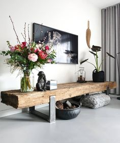 a wooden table with vases and flowers on it in front of a large window