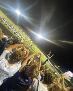 a group of people standing on top of a soccer field holding hands in the air