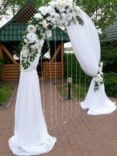 a wedding arch decorated with white flowers and greenery