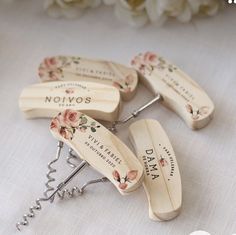 four wooden bottle openers with flowers on them sitting on a table next to white roses