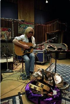 a man sitting on top of a purple bag next to a guitar and other musical instruments