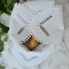 two pieces of bread are in a paper bag on a marble surface with green leaves