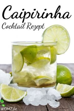 a glass filled with ice and limes on top of a wooden table