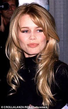 a woman with blonde hair and blue eyes posing for a photo in front of photographers