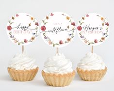 three cupcakes with white frosting and flowers on top, one has a name