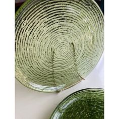 two green glass plates sitting on top of a white countertop next to each other