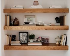 three wooden shelves with books and vases on them