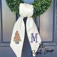 a christmas wreath on the front door with monogrammed letters and an embroidered tree