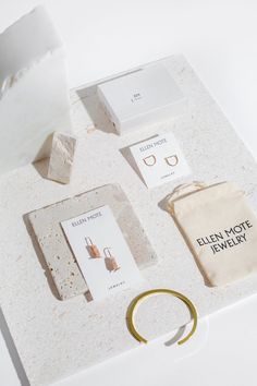 an assortment of jewelry and accessories on a white counter top, including a gold ring