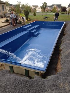 an empty swimming pool with water coming out of the bottom and people standing in the background