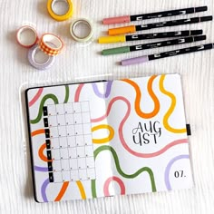 an open planner with markers, tape and washi tapes next to it on a white surface