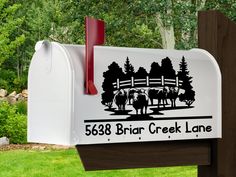 a white mailbox with black and red lettering on it in front of some trees