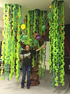 a man standing in front of a tree made out of green plastic vines and flowers