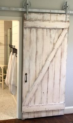 an open barn door in a bathroom with towels hanging on the hooks and towel rack