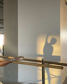 the shadow of a person holding a tennis racket in front of a white wall