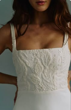 a woman in a white dress with her hands on her hips