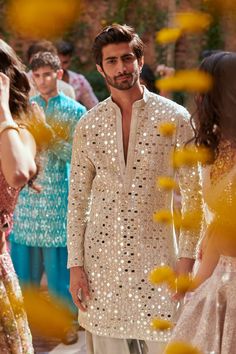 a man in a white outfit standing next to other people and looking at each other