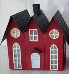 a red toy house with two windows and a black roof