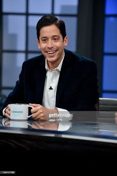 the late show host is smiling while holding a coffee mug