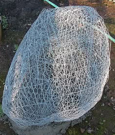 a rock covered in wire sitting on the ground