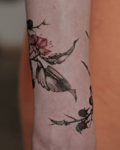 a woman's arm with flowers and leaves on it