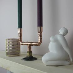 a couple of candles sitting on top of a table next to a white vase with a purple candle in it