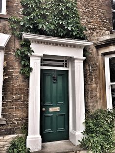 a green door is in front of an old brick building with ivy growing on it