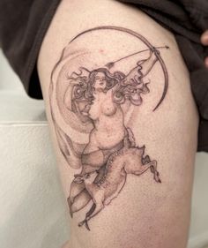 a woman with a bow and arrow tattoo on her thigh is holding onto a horse