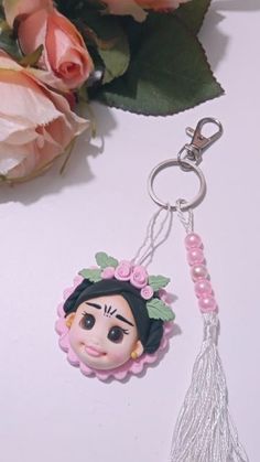 a keychain with a doll on it next to some flowers and a rose