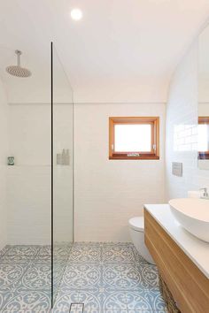 a bathroom with blue and white tile flooring next to a sink, toilet and shower