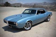 a blue muscle car parked in the desert